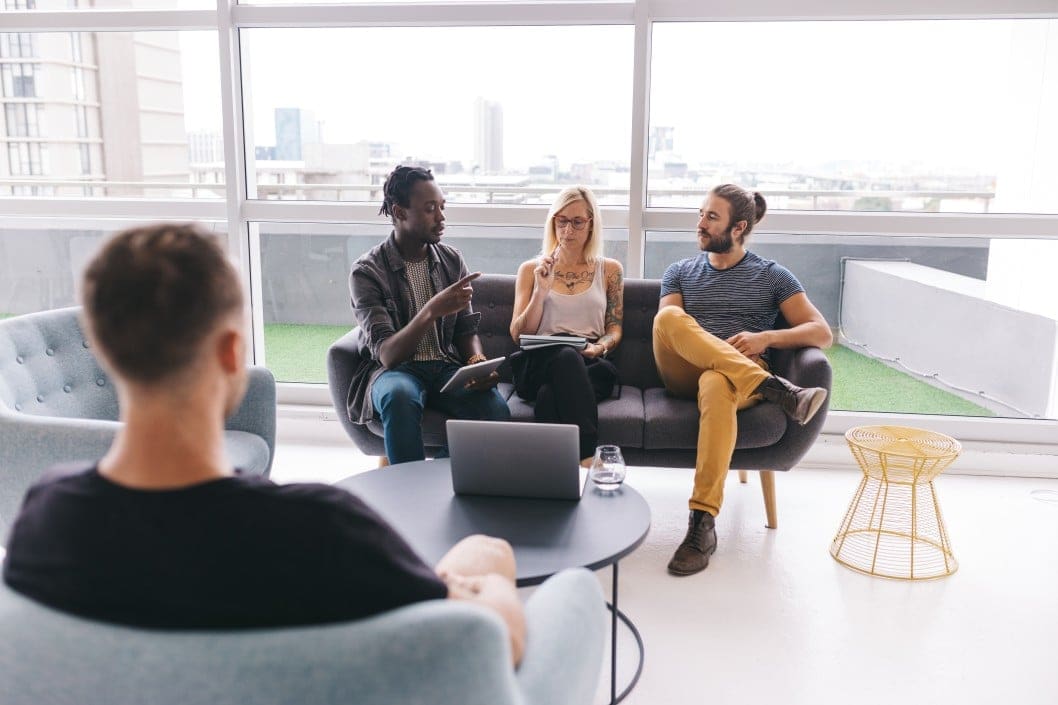 Three people on a couch and one on a chair talking