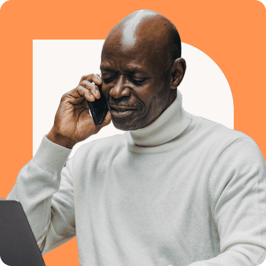 An elderly black man talking on a phone while looking at a laptop, set against an abstract orange background.
