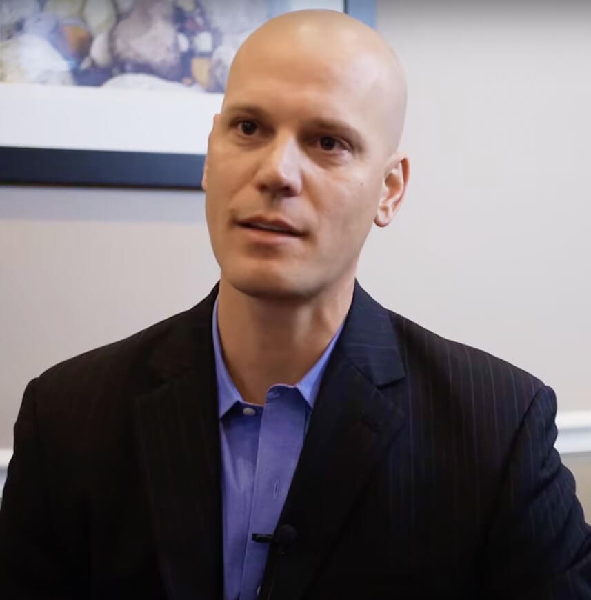 Bald man in a business suit participating in an interview.